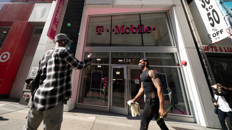 A man uses a mobile phone outside a T-Mobile store, Monday, April 19, 2021, in New York. The...