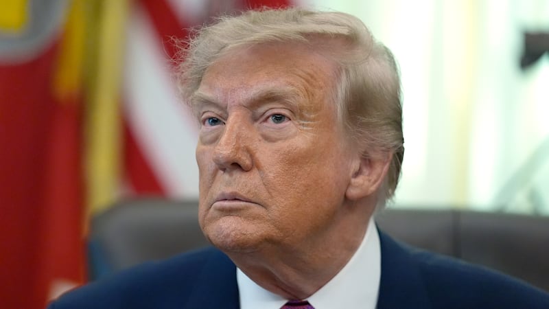 President Donald Trump listens to a question from a reporter in the Oval Office of the White...